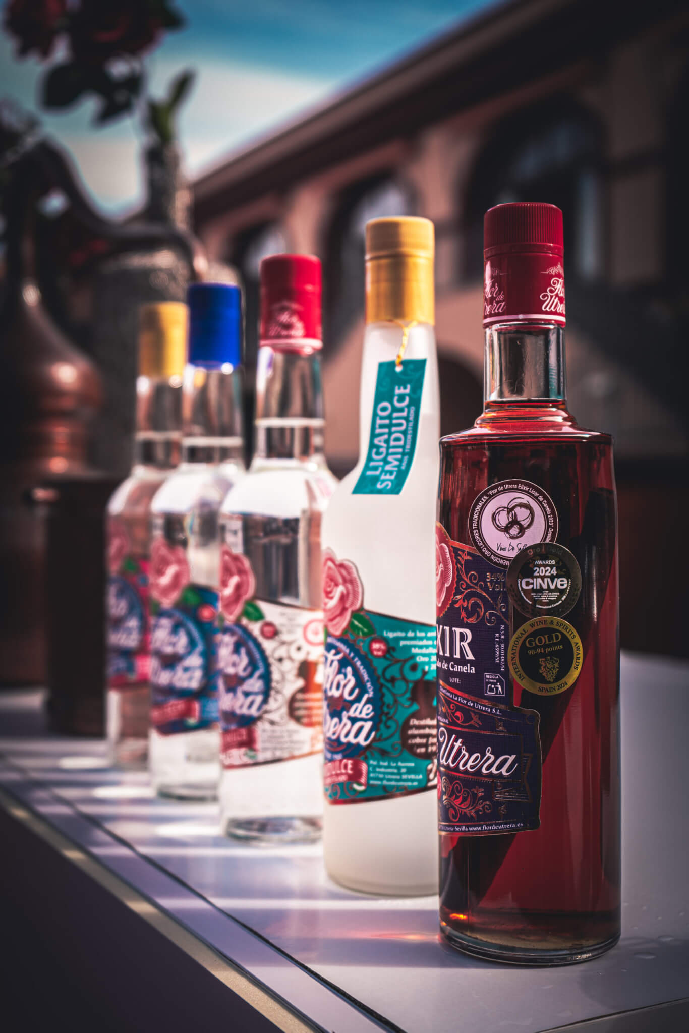 Botellas de anís y licor de canela de La Flor de Utrera alineadas en una mesa exterior.