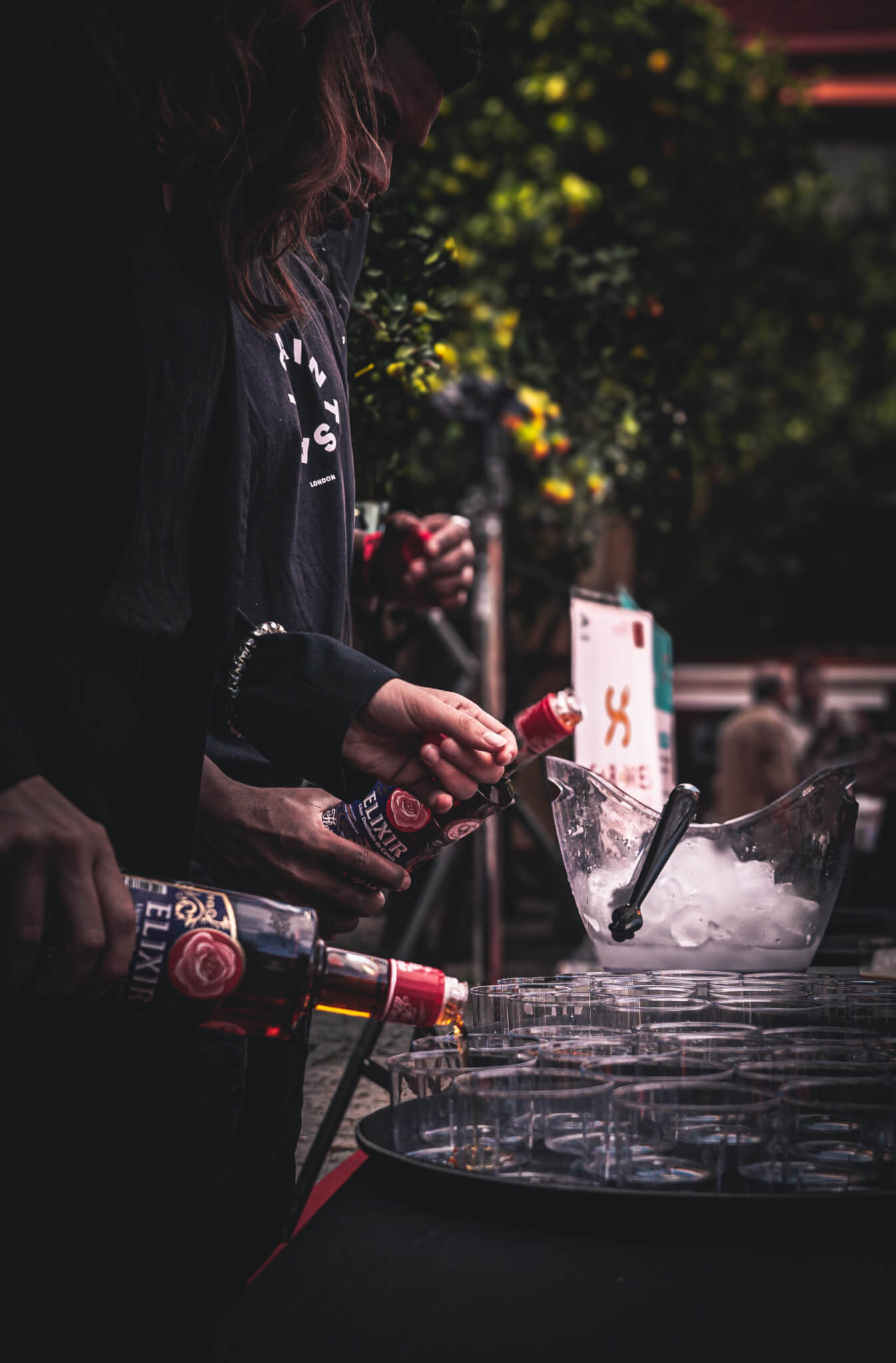 Personas sirviendo Elixir de La Flor de Utrera en vasos para una degustación en un evento.