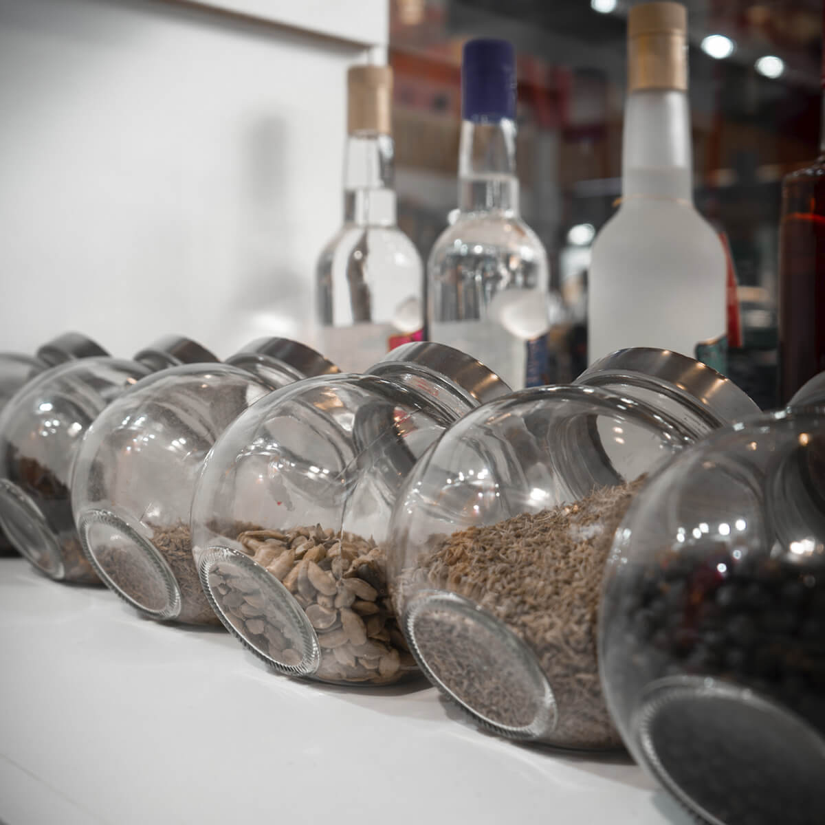 Detalle de tarros con botánicos como anís y enebro, junto a botellas de anís de La Flor de Utrera en el stand del Salón H&T Málaga 2025.